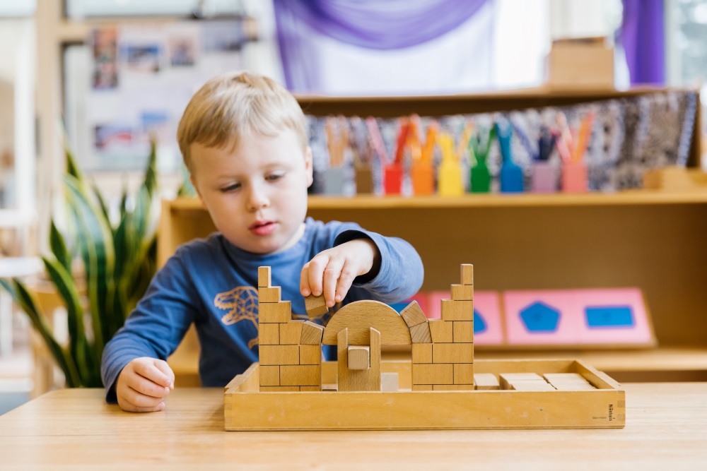 Student works with wooden blocks at Hills Montessori Preschool