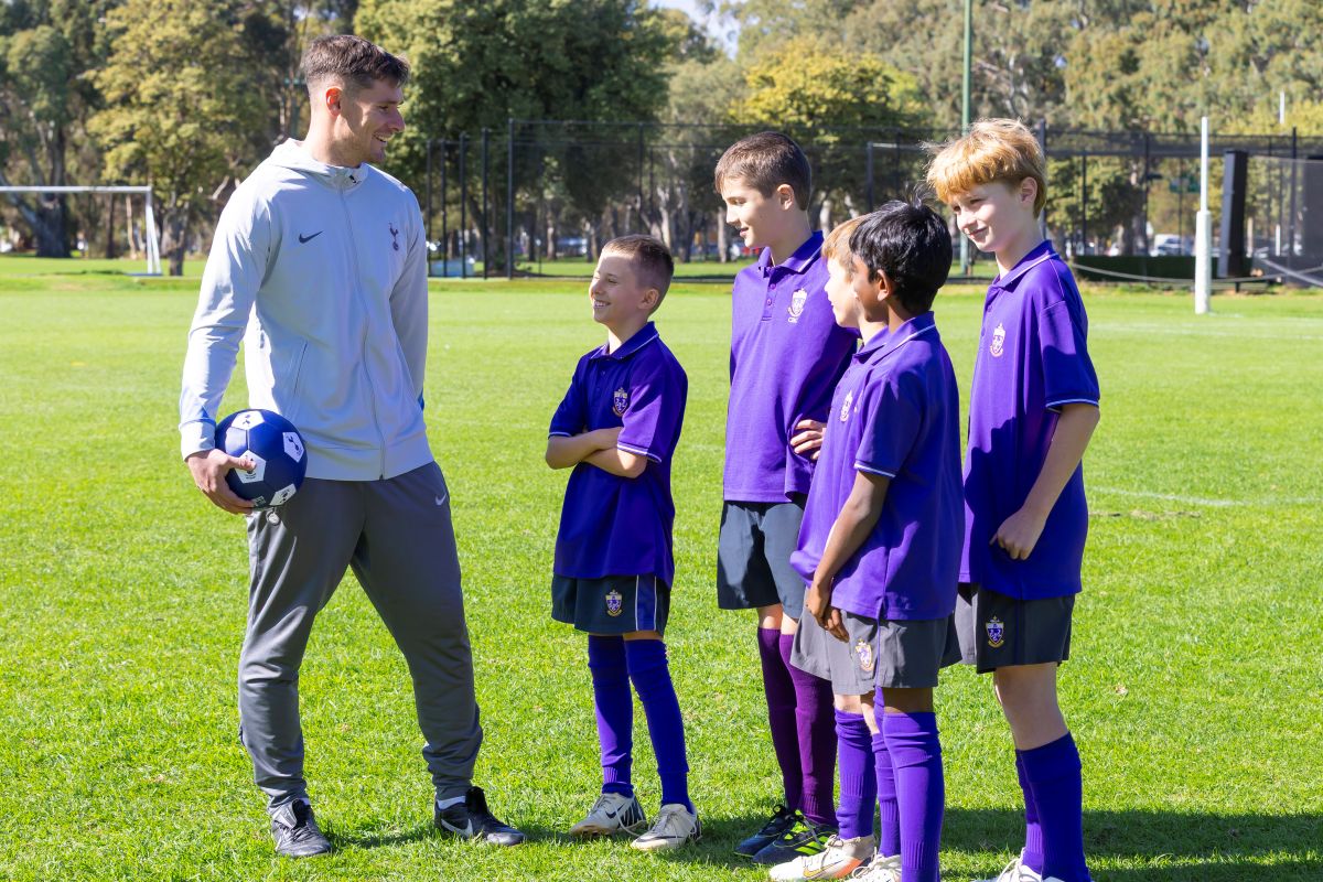 A group of boys standing together on a grassy field, smiling and engaging with one another.