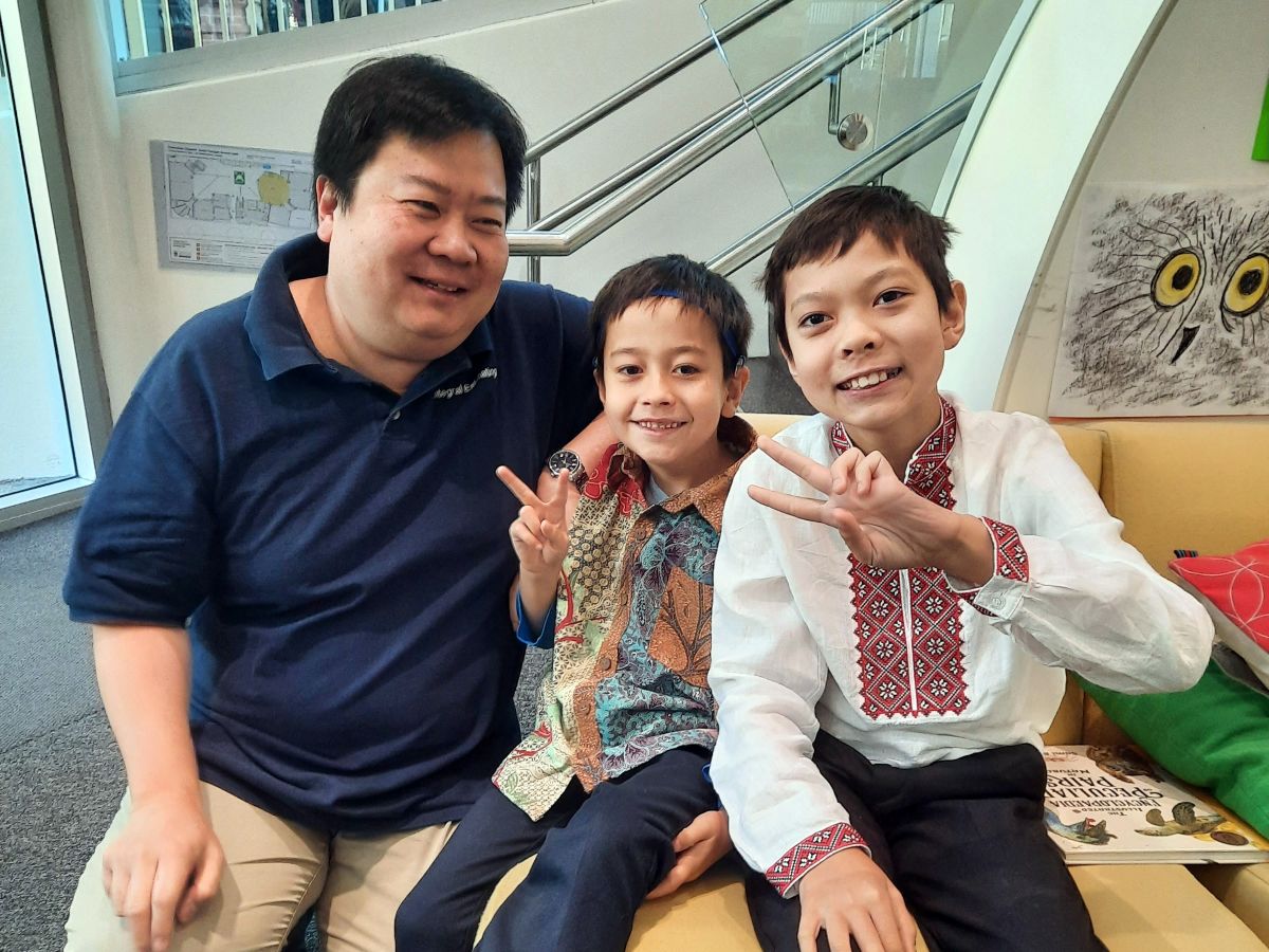 Two boys and an Asian man smile together for a photo, showcasing a friendly moment.
