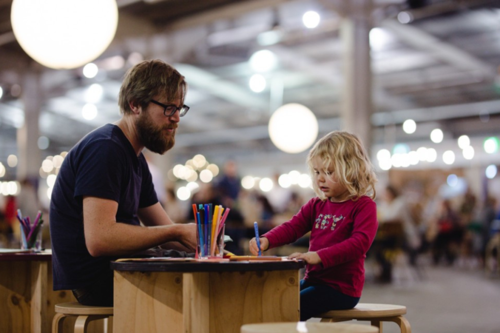 A man and a little girl enjoy coloring together at a table filled with vibrant coloured pencils at Bowerbird, Adelaide.