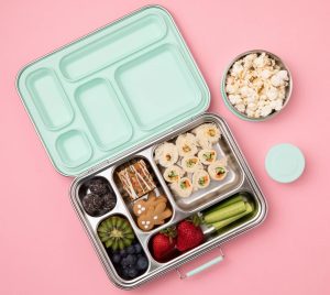 Teal lunch box filled with rolled sandwiches, popcorn, kiwi fruit and other healthy snacks.