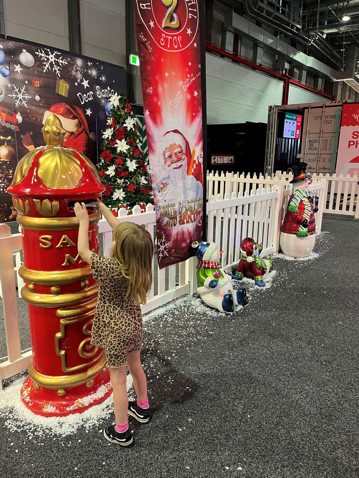 A little girl joyfully plays with a red mailbox