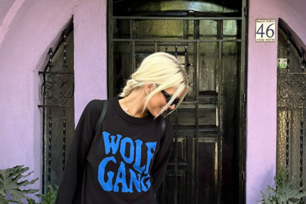 A woman in a black sweatshirt featuring the words "wolf gang" printed on the front.