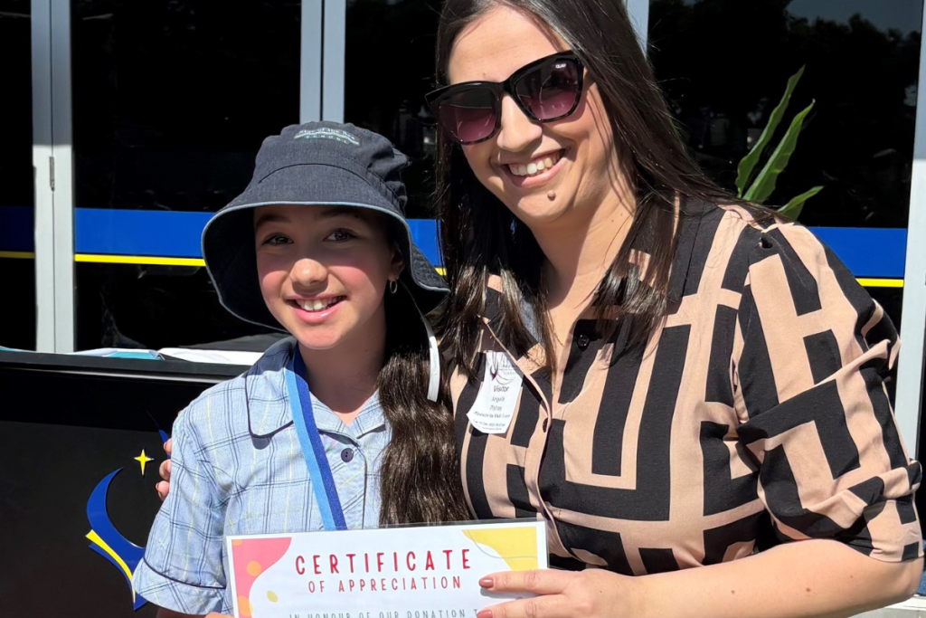 A woman and a young girl proudly display a certificate together.