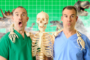 Two men in scrub suits stand beside a skeleton, showcasing a medical or educational setting.