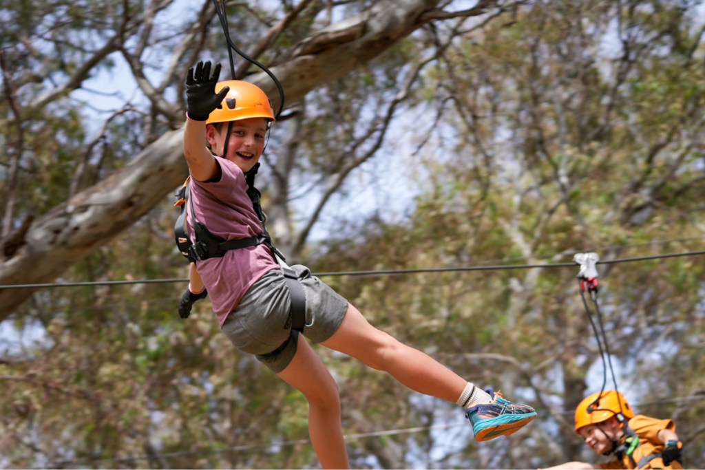 A young child experiencing the thrill of ziplining on a rope course, embodying adventure and joy in a natural setting.