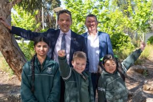 Two people stand with three school children.