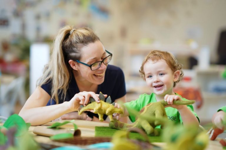 Early learning educator laughs with child.