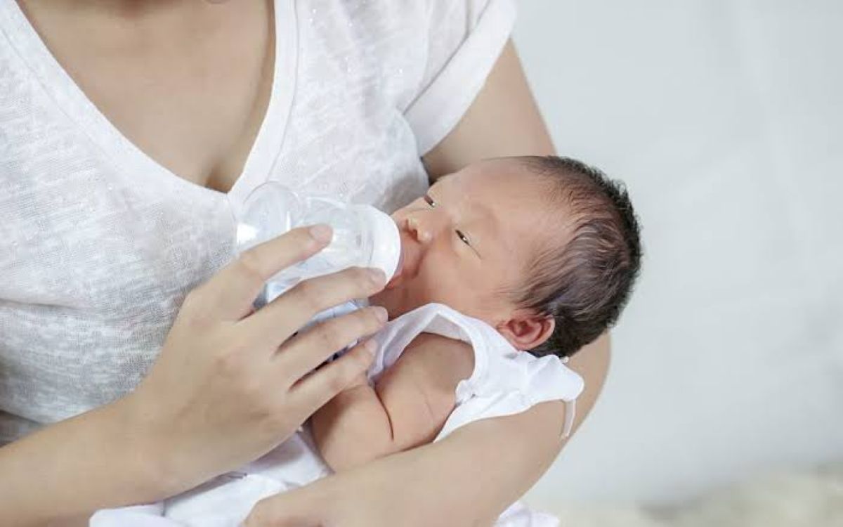 Mother feeds baby bottle.