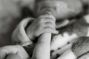 Preterm baby holding mother's finger.