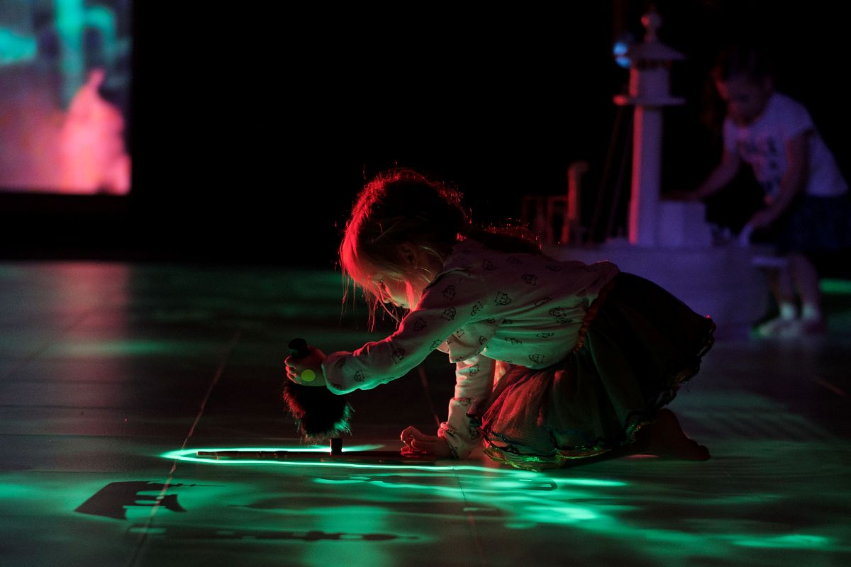 A young girl joyfully playing with a colorful light-up toy in a bright, cheerful setting.