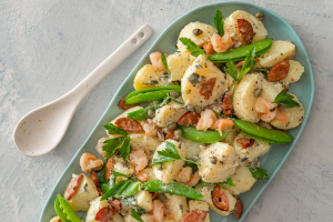 A plate featuring a colorful mix of potatoes, green peas, and succulent shrimp.