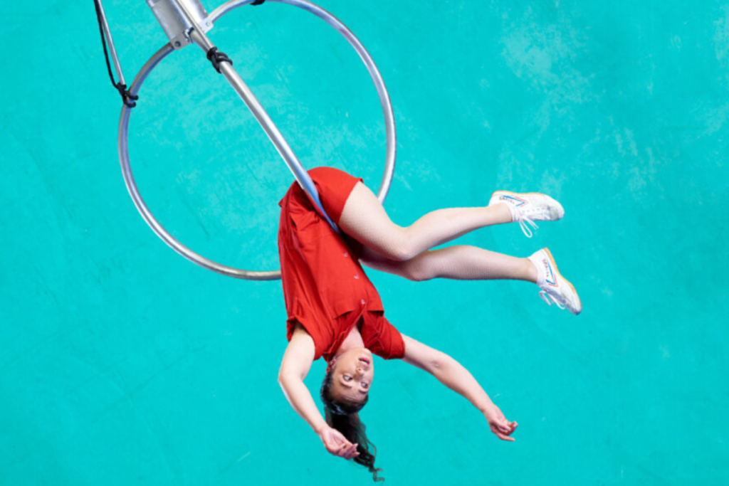 woman performs an upside-down pose on a hoop, showcasing her strength and flexibility in a captivating aerial display.