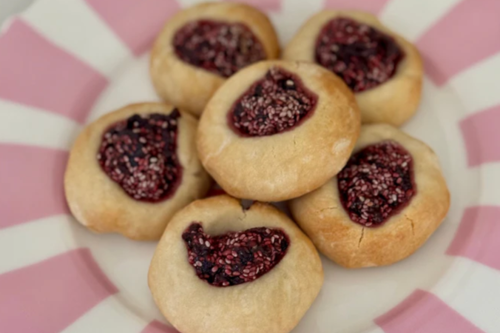 A plate filled with delicious cookies, each featuring a vibrant raspberry filling in the center.