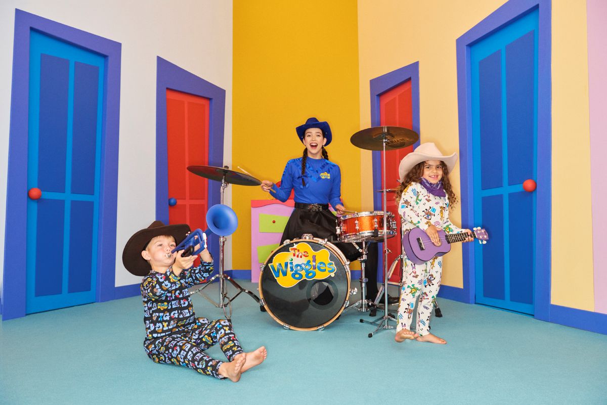 Two children in pajamas joyfully playing music together in a vibrant, colorful room filled with toys and decorations.