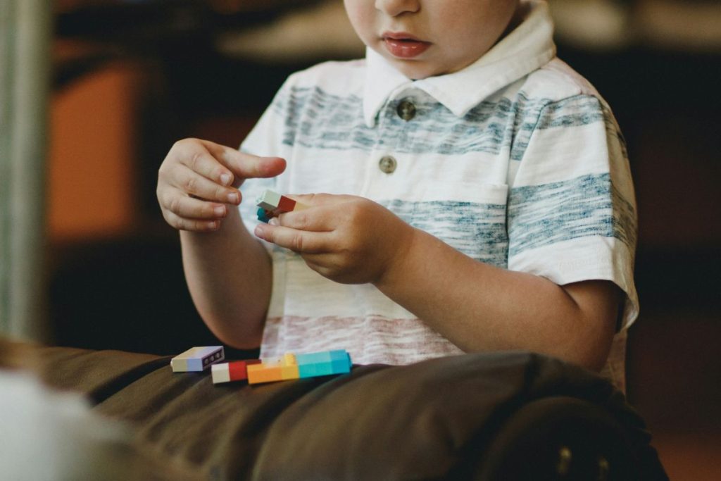 A young boy joyfully stacking colorful blocks on the floor, showcasing creativity and playfulness.