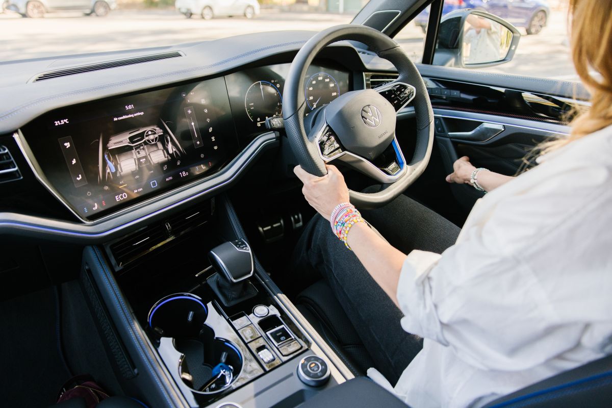  A woman focused on driving, with a modern car dashboard display visible in front of her.