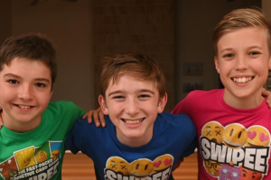 Three boys wearing colorful shirts adorned with smiley faces, showcasing cheerful expressions and a sense of camaraderie.