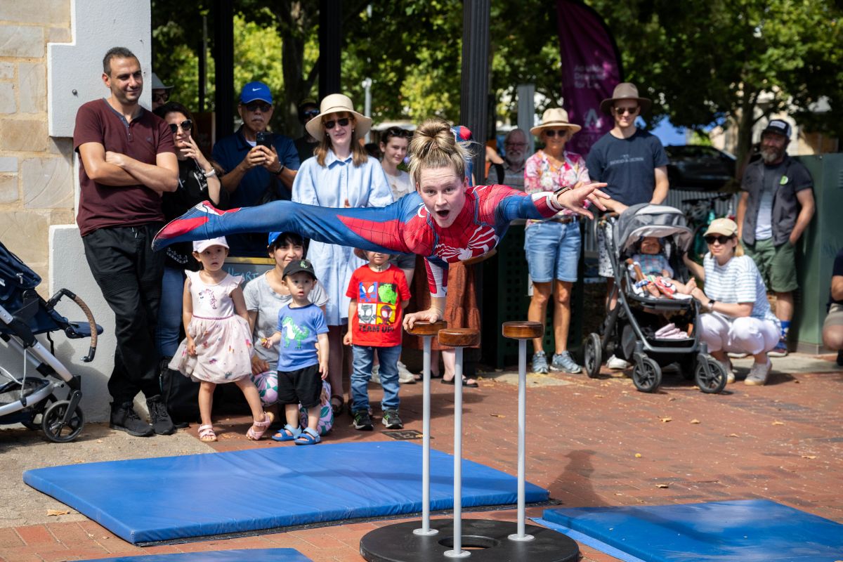 A young girl skillfully performs on a balance beam while an attentive crowd watches her every move.