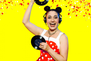 A woman in a Mickey Mouse costume joyfully holds up two record players, showcasing her playful spirit and love for music.