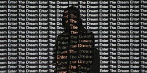 A person stands silhouetted against a wall featuring the phrase "enter the dream."