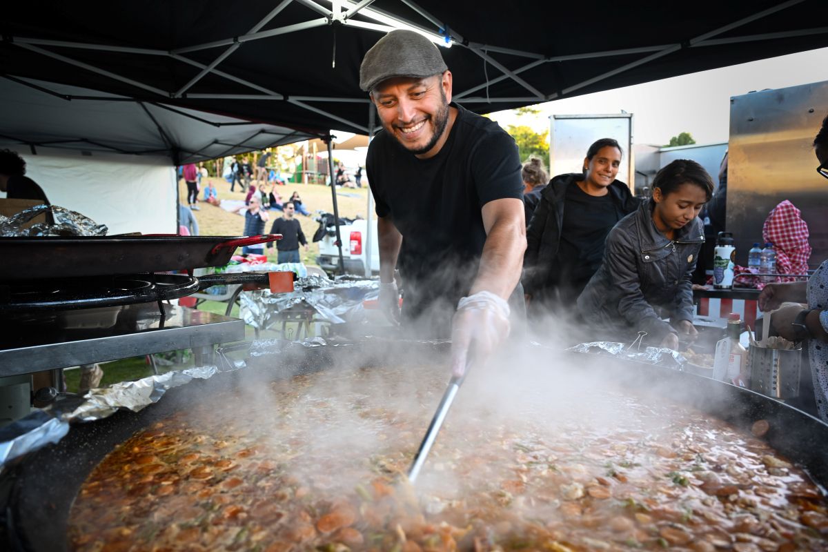 A man skillfully cooks food in a large pan, showcasing his culinary expertise in a vibrant kitchen setting.