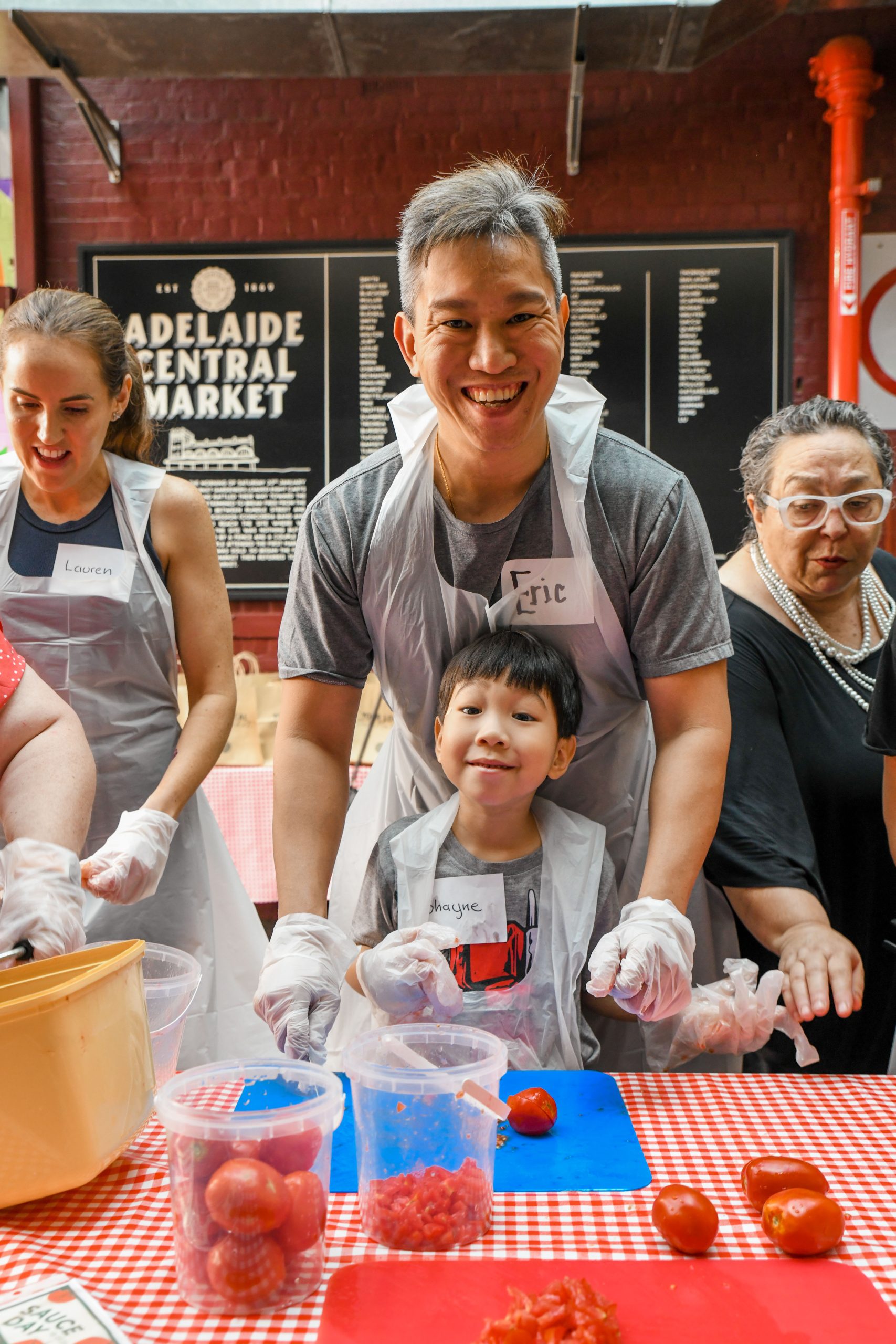  A cheerful group of people smiles together while preparing a meal in a bright kitchen.