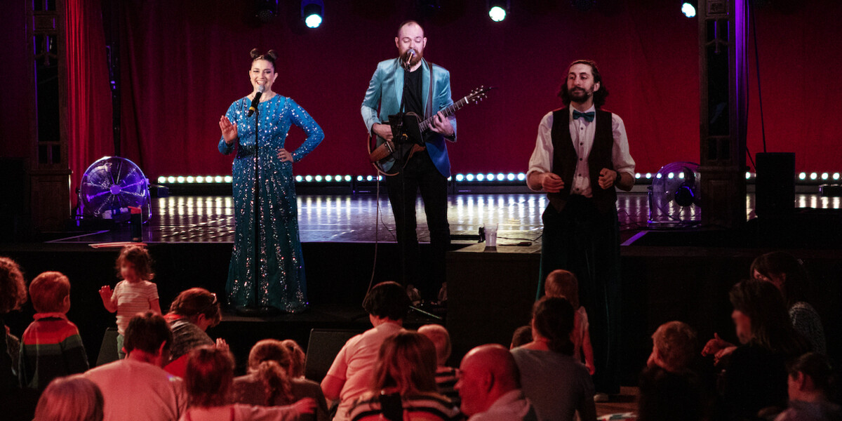 A group of people on stage, with a man playing guitar, creating a lively musical atmosphere.