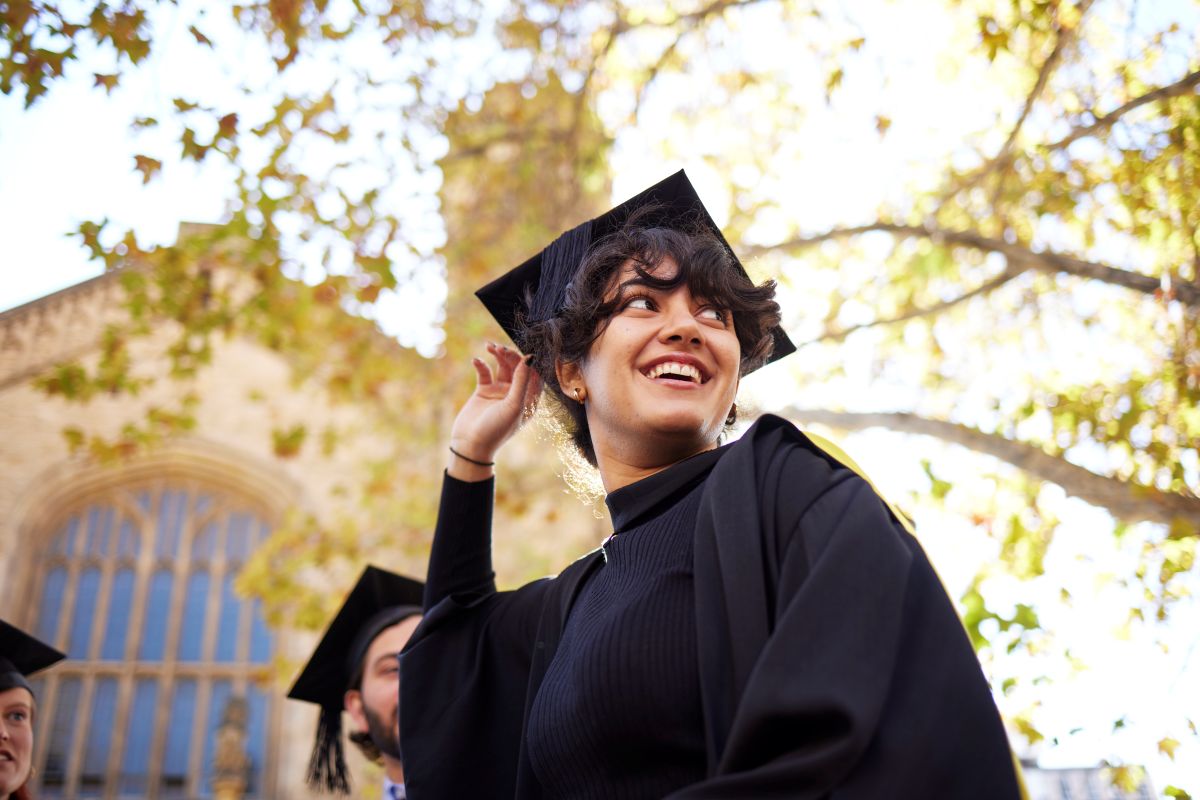 A woman in a graduation gown smiles brightly, marking her graduation milestone.