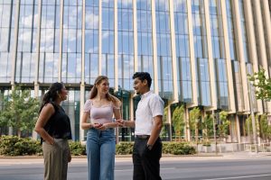 Three people engaged in conversation outside a building, sharing ideas and enjoying the moment together.