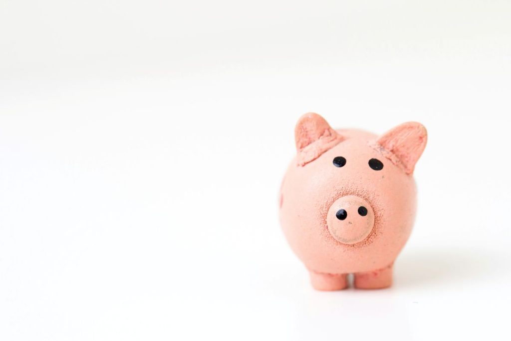 A small pink pig figurine sits on a clean white surface, showcasing its cute and charming design.