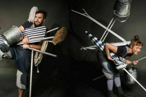 Two people smile while posing with a broom and a bucket, suggesting a playful cleaning theme.