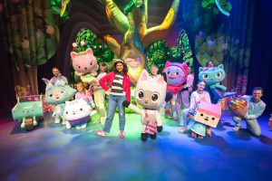 A group of children smiling and posing with various stuffed animals in a bright outdoor setting.