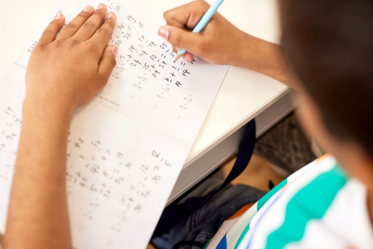 A child focused on writing with a pencil on a piece of paper, showcasing creativity and concentration.