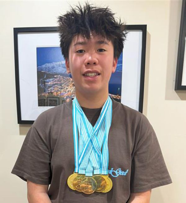 A young man proudly wearing a medal around his neck, smiling with a sense of achievement.