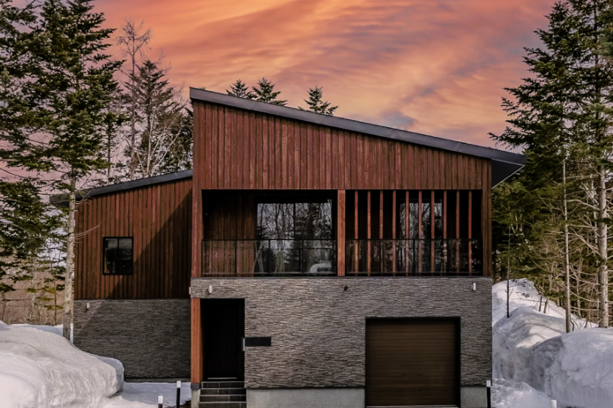 A modern house with a sleek design and a driveway covered in fresh snow, creating a serene winter scene.