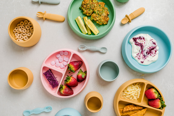 A collection of vibrant plates and bowls filled with various colorful foods arranged on a table.