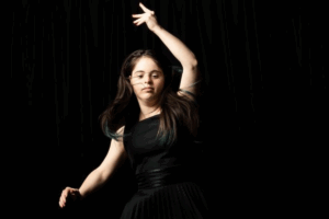 A woman in a black dress dances gracefully, showcasing her movements and joy.