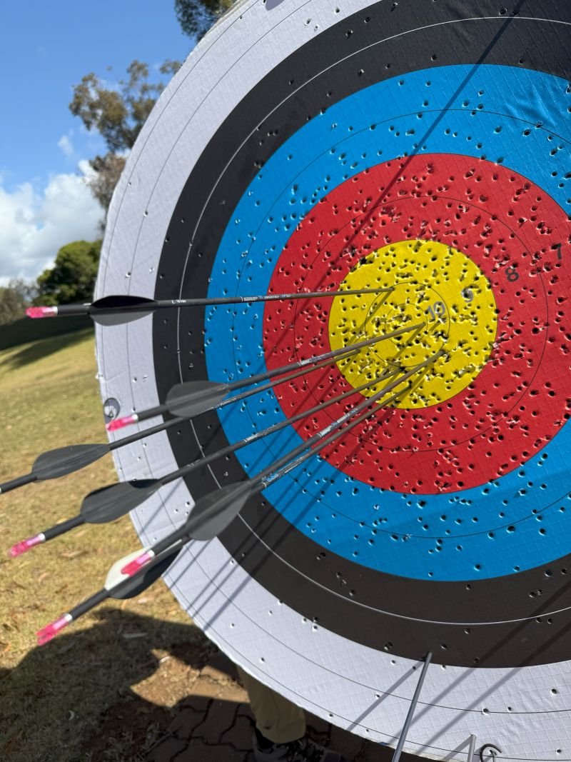 Close-up of an archery target featuring several arrows embedded in the colorful bullseye.