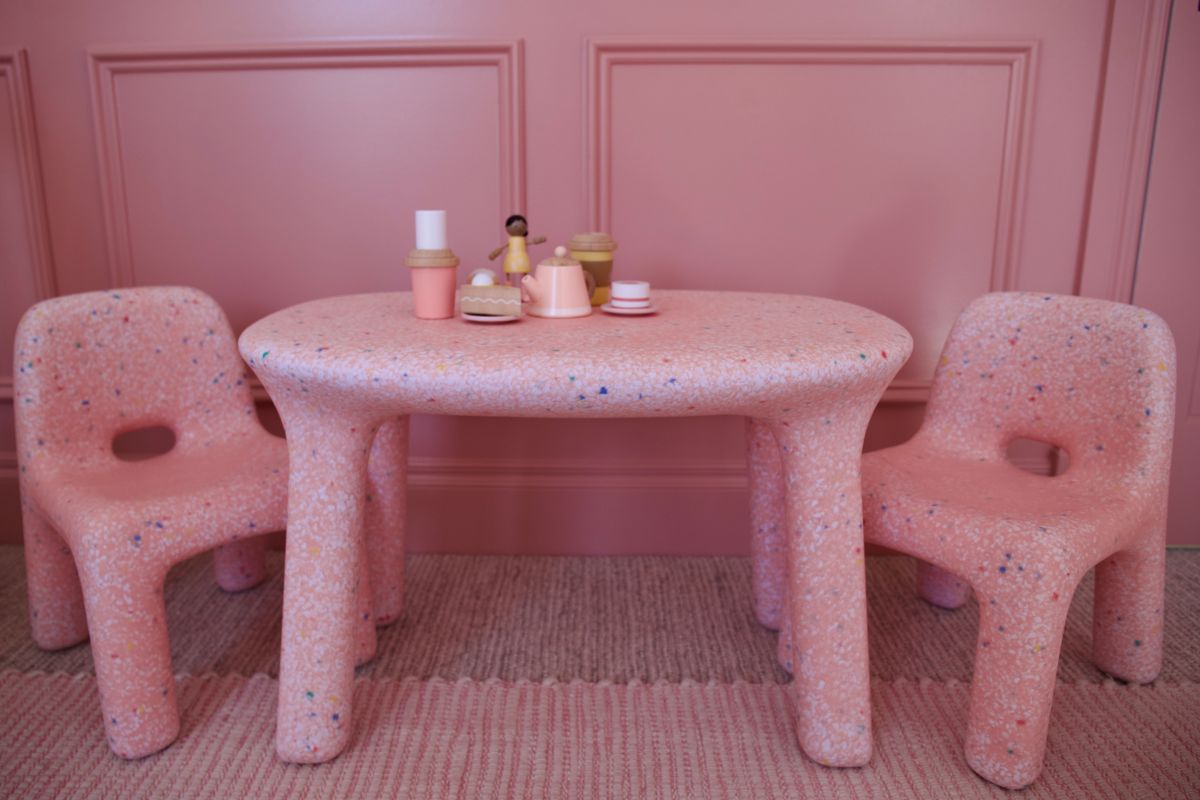 A pink table surrounded by two matching pink chairs in a bright, cheerful setting.
