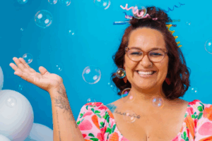 A woman in a vibrant dress surrounded by floating bubbles in a cheerful outdoor setting.