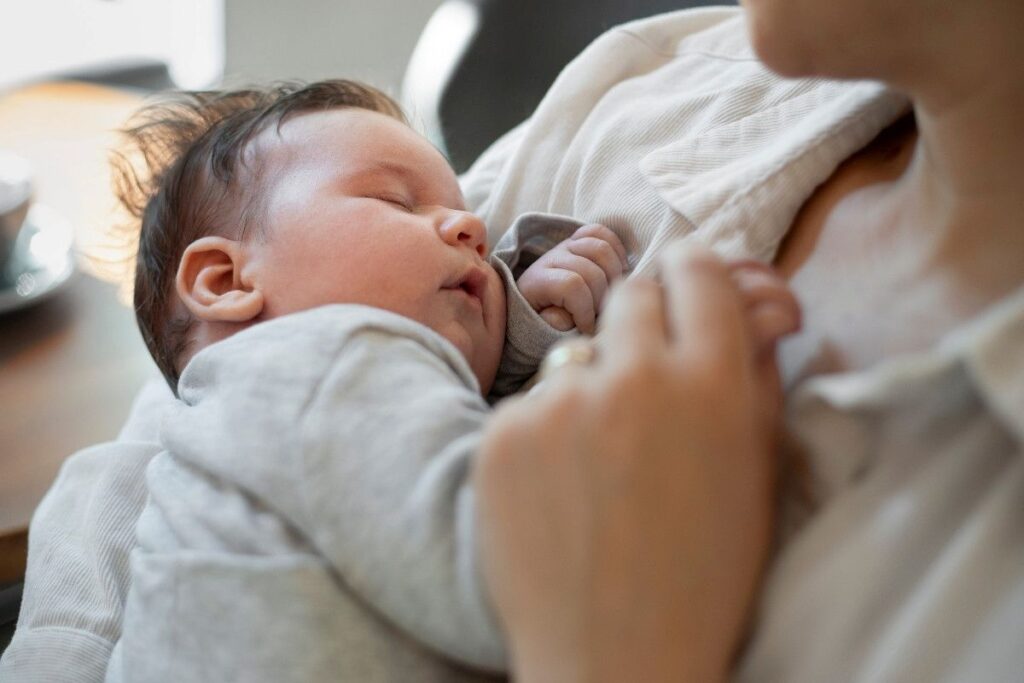 A woman breastfeeding a baby, gently cradling the child in her arms with a nurturing expression.