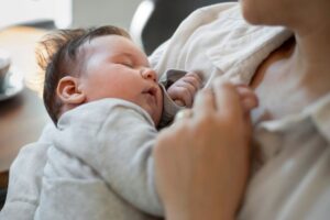 A woman breastfeeding a baby, gently cradling the child in her arms with a nurturing expression.