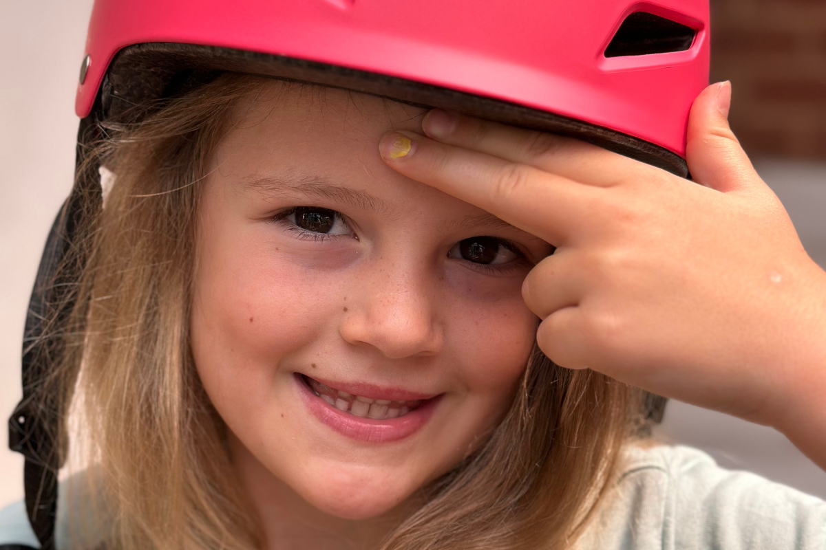  young girl wearing a helmet, smiling and ready for an outdoor adventure.