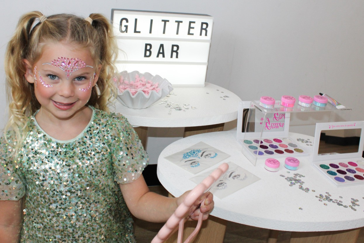 A young girl joyfully holds a colorful glitter bar, showcasing her excitement and creativity.