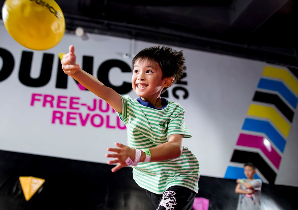 A young boy throws a frisbee in a colorful indoor play area filled with soft play equipment.
