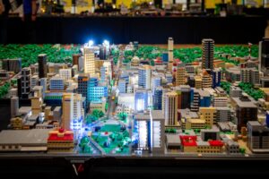 A colorful Lego city built on a table, featuring various buildings, vehicles, and miniature figures.