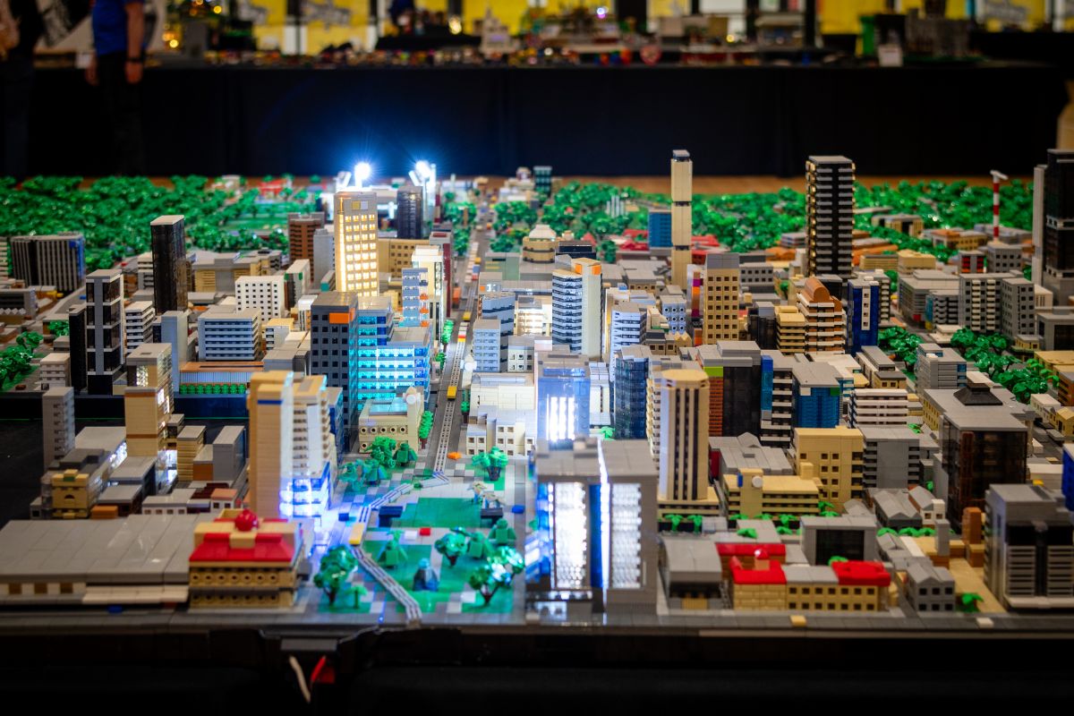 A colorful Lego city built on a table, featuring various buildings, vehicles, and miniature figures.