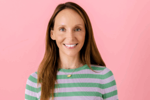 A woman wearing a striped shirt smiles warmly at the camera.