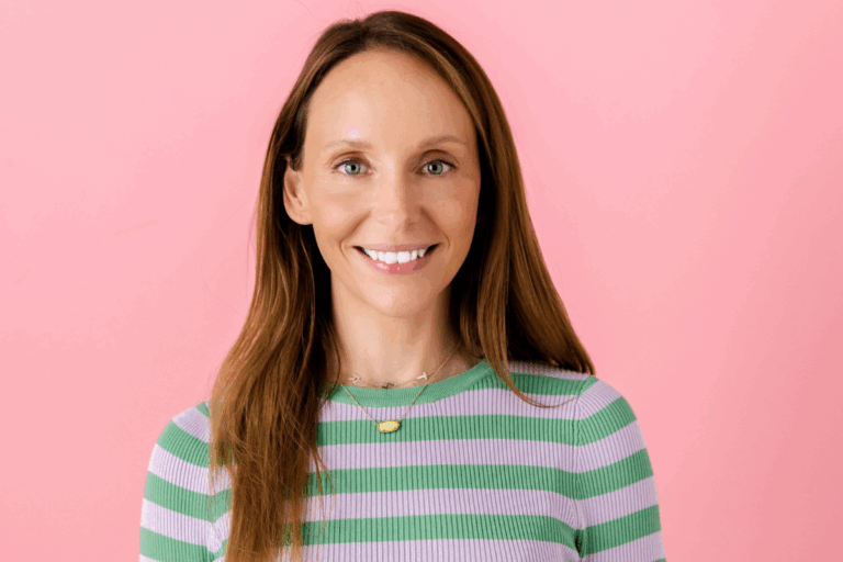 A woman wearing a striped shirt smiles warmly at the camera.